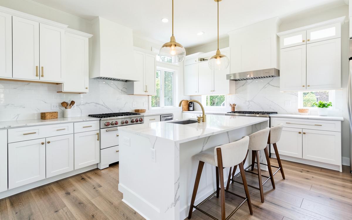 Remodeled kitchen with white shaker cabinets, quartz island and brass fixtures